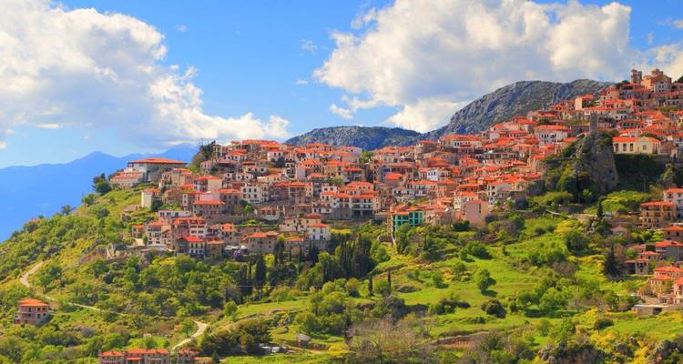 Picturesque hillside town of Arachova with red-tiled roofs set among lush green mountains.