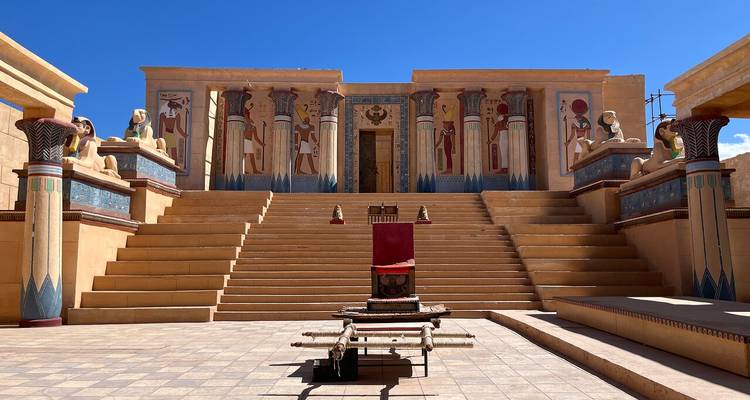Plateau de tournage avec grand escalier et colonnes égyptiennes peintes sous un ciel bleu dégagé aux studios de Ouarzazate.