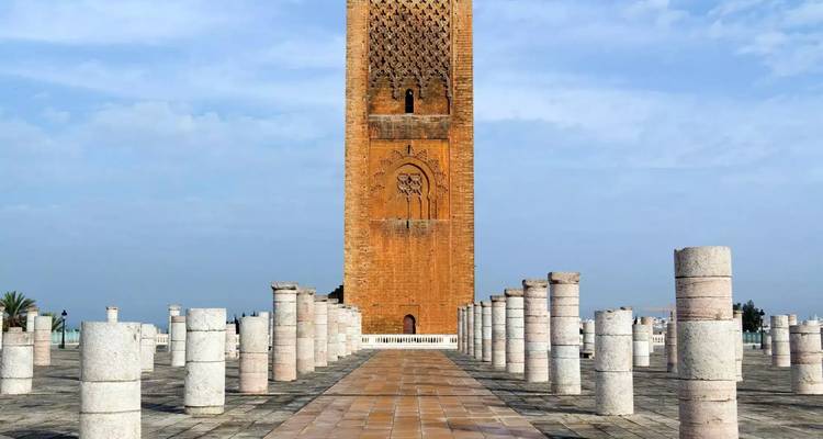 La Tour Hassan s'élève au-dessus de rangées de colonnes en marbre à Rabat sous un ciel bleu pâle.