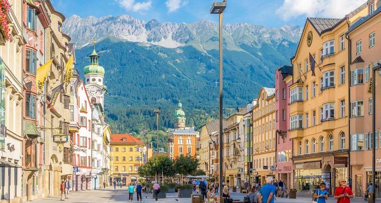 Kleurrijke Innsbruck straat met alpine achtergrond van de Nordkette bergen onder heldere luchten.