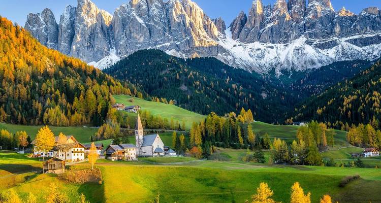 Ansichtkaartperfecte Dolomieten-vallei met piepklein kerkje, alpenweiden en grillige besneeuwde toppen.