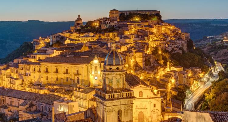 Evening lights illuminate the baroque hilltop town of Ragusa Ibla creating a golden glow at dusk.