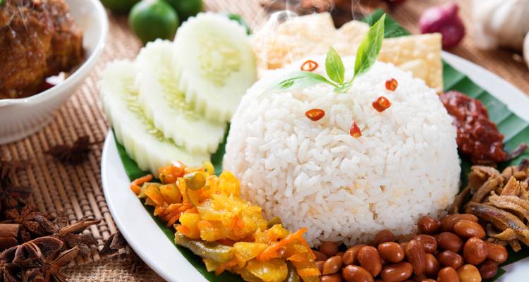 Angerichtetes malaysisches Nasi Lemak mit Reis, Gemüse, Erdnüssen und Sambal, appetitlich präsentiert.