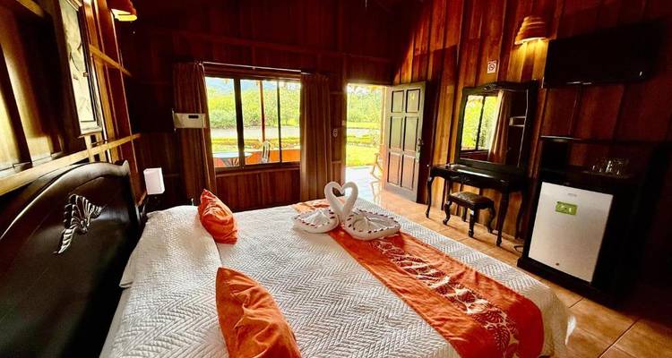 Chambre de cabine en bois douillet avec des serviettes décoratives en forme de cygnes d'amour sur le lit.