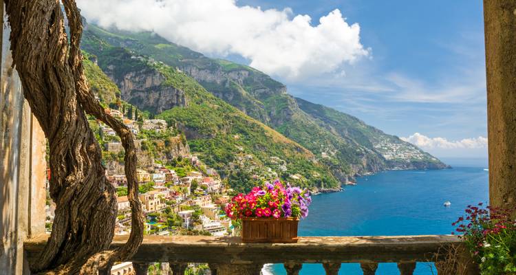 Flower-framed balcony looking out over Positano’s colourful houses and dramatic coastline.