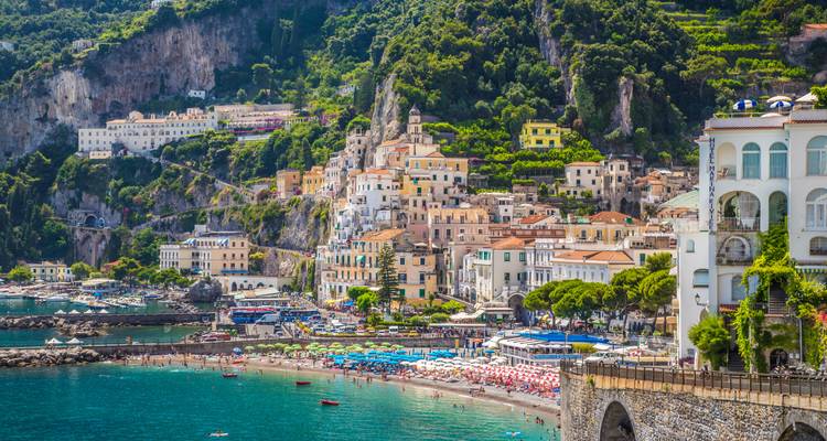 Vibrant seaside town of Amalfi with colourful buildings, beach umbrellas and turquoise water.
