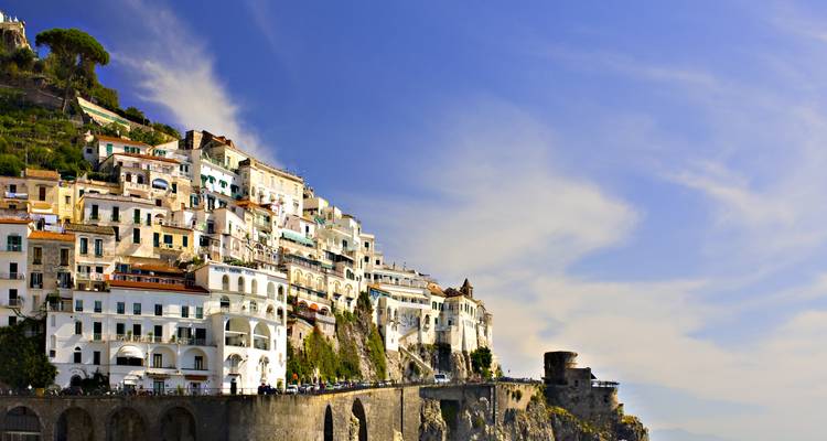 Amalfi’s cliff-hugging houses glowing in warm afternoon light against a big blue sky.