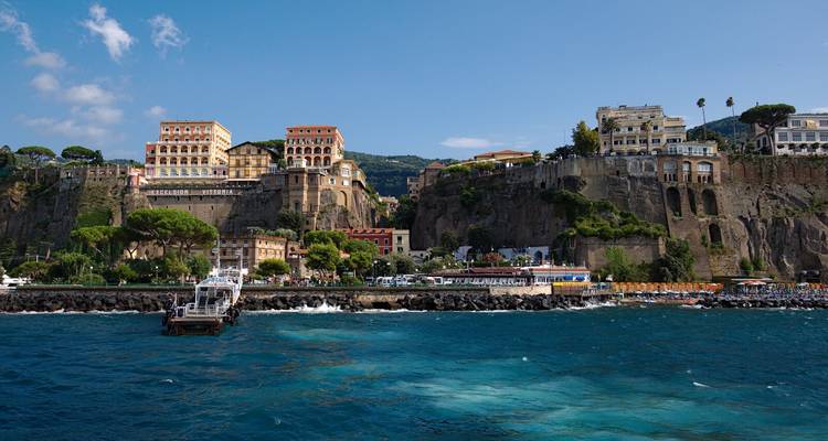 View from the water of Sorrento’s cliff-top hotels and buildings above the deep blue bay.