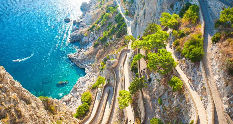 Aerial view of the winding Via Krupp footpath descending dramatic limestone cliffs to crystal-clear Capri waters.