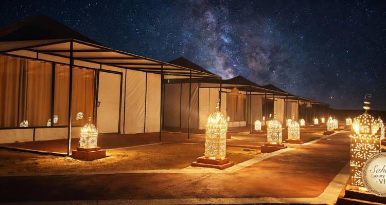Milky Way shining above a luxury Sahara tent camp lined with ornate lanterns.
