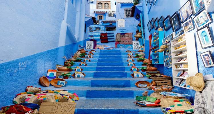 Vibrant blue stairway lined with handmade crafts in Chefchaouen medina