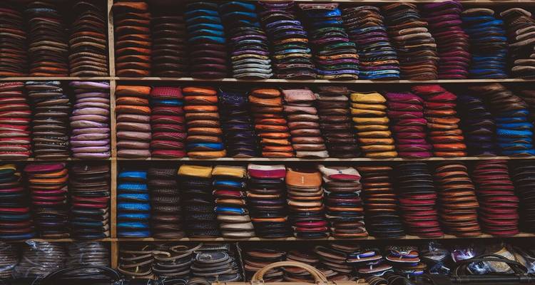Stacks of colorful leather slippers neatly arranged on shelves in Moroccan market
