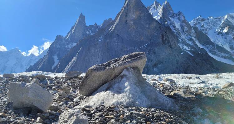 Gletsjermoreïne met uniek paddenstoelvormig ijsblok tegen een achtergrond van steile rotspieken.