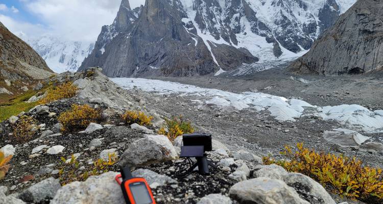 Rotsachtige bergkam boven een gletsjer met navigatie- en camera-apparatuur geplaatst op rotsblokken op de voorgrond.