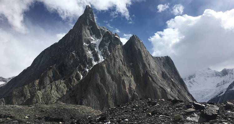 Scherpe granieten piek die oprijst in dramatische wolken boven donkere rotswanden in de Karakoram.