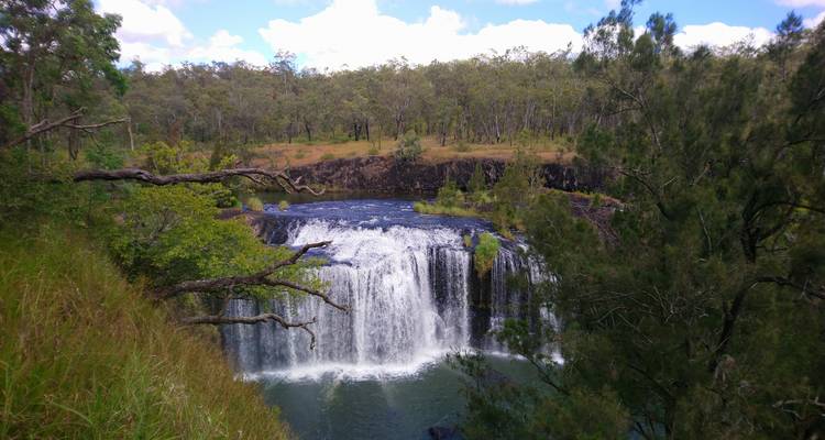 A picturesque waterfall tumbles over a basalt ledge into a forested gorge.