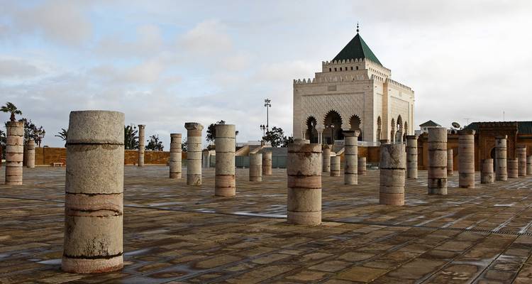 Mausoleum of Mohammed V framed by rows of stone columns on a vast paved esplanade under soft light