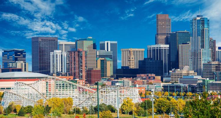 Gros plan sur la ligne d'horizon moderne de Denver avec montagnes russes et arbres d'automne au premier plan
