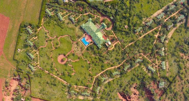 Drone view of a secluded safari lodge complex surrounded by lush greenery.