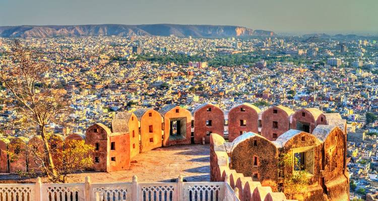 Depuis les anciens murs d'un fort, une vue panoramique révèle le paysage urbain rose s'étendant de Jaipur contre les collines lointaines.
