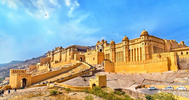 Les murs imposants en grès jaune d'Amber Fort et ses palais ornés s'élèvent sur la colline sous un ciel bleu brillant.