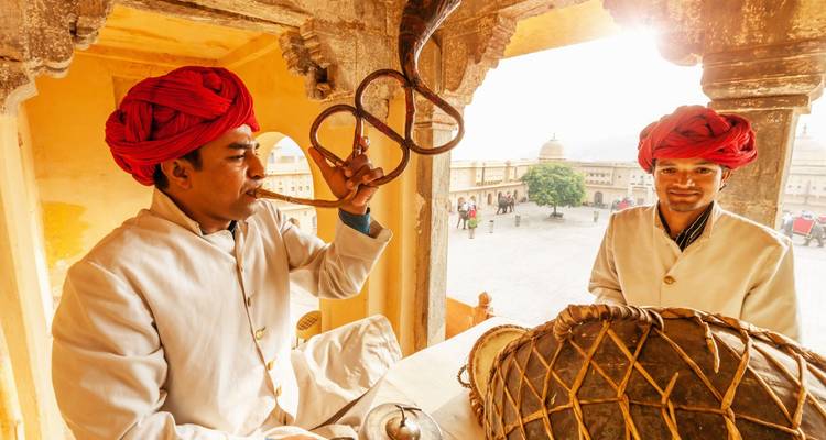 Des musiciens traditionnels portant de brillants turbans rouges jouent du cor et du tambour sous les arcades ensoleillées du Fort d'Ambre.