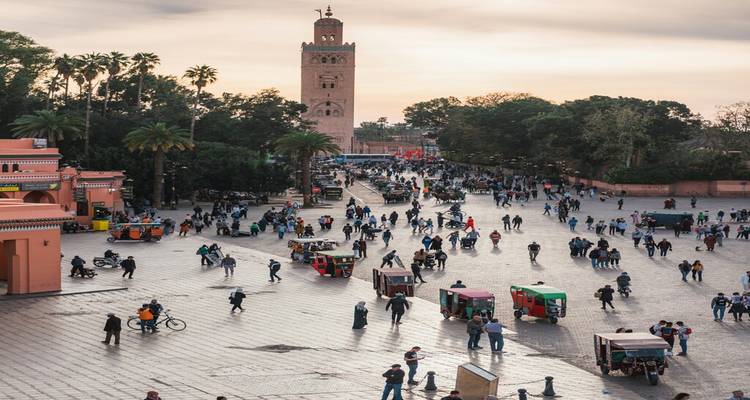 La place animée Jemaa el-Fna à Marrakech avec ses foules, ses étals de nourriture et la Mosquée Koutoubia au crépuscule