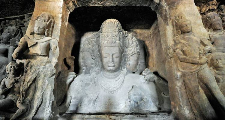 Ancient Trimurti sculpture carved inside Elephanta Caves depicting three-headed Shiva