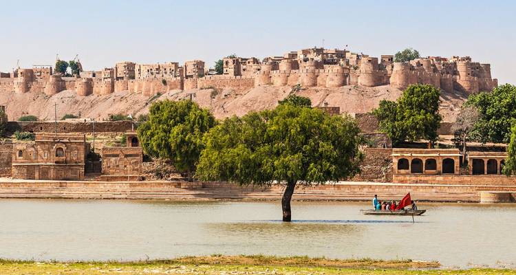 Historische ommuurde citadel van Jaisalmer rijzend boven paviljoen aan het meer met kleine boot