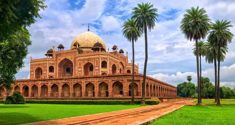 Majestic red-sandstone Humayun’s Tomb framed by tall palm trees against a bright sky.