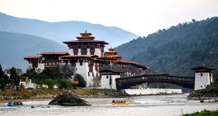Majestätische Punakha Dzong erstreckt sich über einen Bergfluss, während Flößer unten paddeln