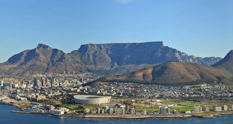 Daytime aerial of Cape Town waterfront with stadium and iconic Table Mountain ridge dominating the skyline.