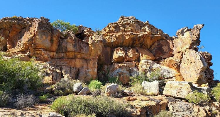 Sunlit orange sandstone cliffs and boulders against a deep blue sky in the Cederberg Wilderness.