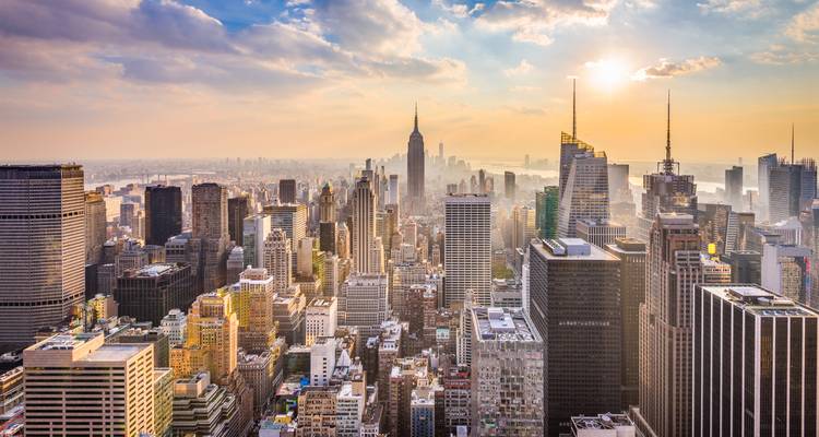 Panorama de l'heure dorée de Midtown Manhattan avec des gratte-ciel illuminés par le soleil et un horizon lointain brumeux.