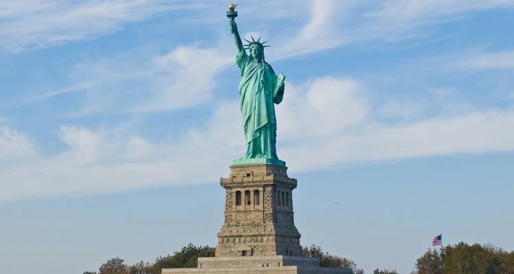 The Statue of Liberty stands tall against a blue sky streaked with wispy clouds.