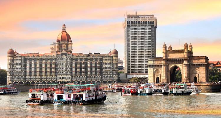 Boats glide before the Gateway of India and Taj Mahal Palace Hotel at sunset in Mumbai harbour.