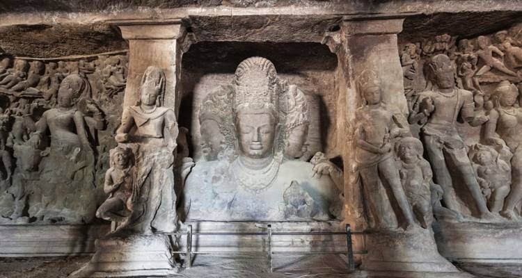 Carved rock relief of the Trimurti and attendant figures inside Elephanta Caves.