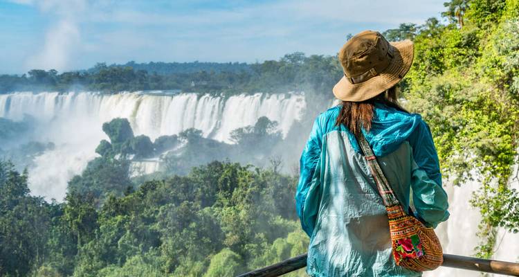 Female traveller in hat admiring expansive view of Iguazu Falls from a lookout