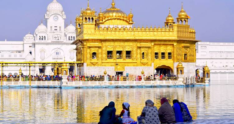 Golden Temple shimmering in sunlight with devotees seated by the holy pool at Amritsar.