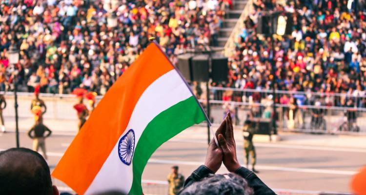 Indian tricolour flag held aloft by applauding spectators during a patriotic ceremony.