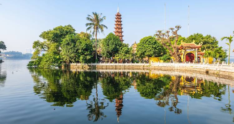 Tran Quoc Pagoda reflects perfectly in a tranquil lake under a clear Hanoi sky.