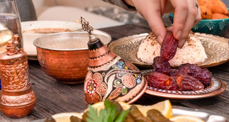Close-up of traditional Moroccan dishes with a hand picking dates from a plate.