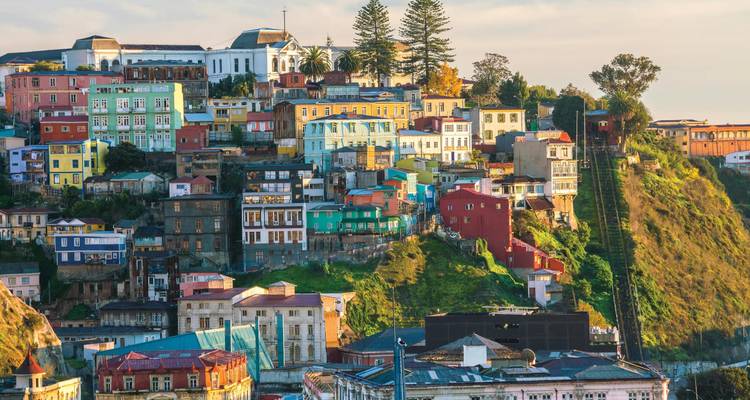Colorful stacked houses cascade down the steep hillsides of Valparaíso at sunset.