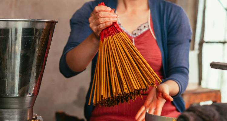Gros plan d'une femme tenant un paquet fraîchement attaché de bâtons d'encens.