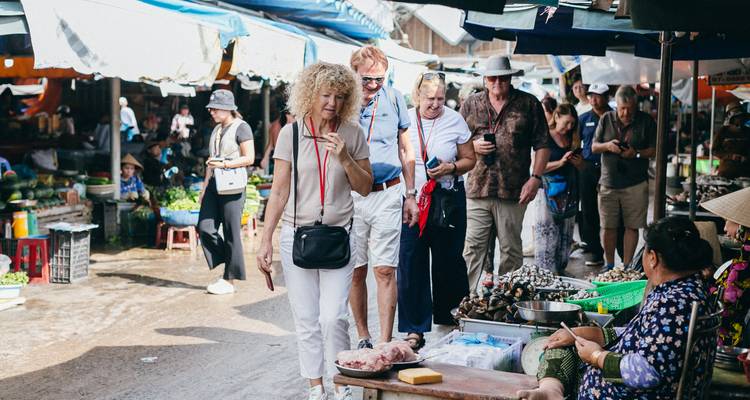 Les touristes feuilletant les étalages et les produits dans un marché vietnamien extérieur animé.