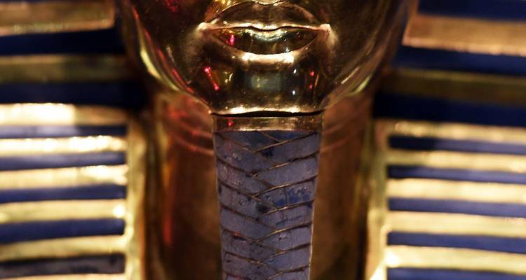 Macro view of the gold and blue striped funerary mask of Tutankhamun focusing on the chin area.