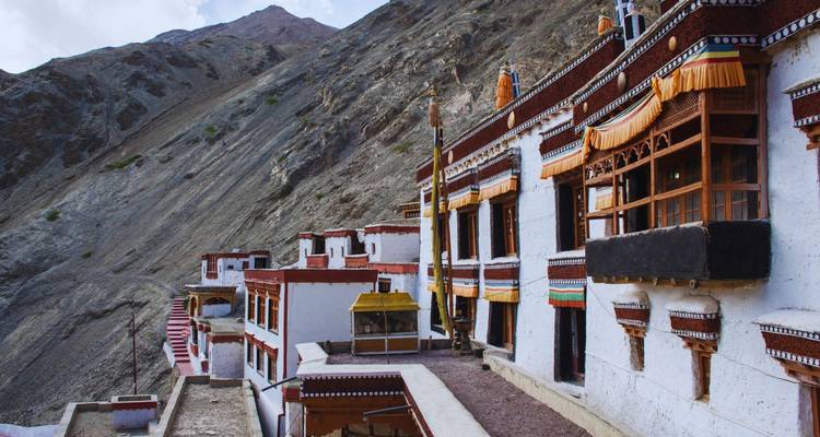 Long white-walled monastery buildings clinging to steep arid hillside.