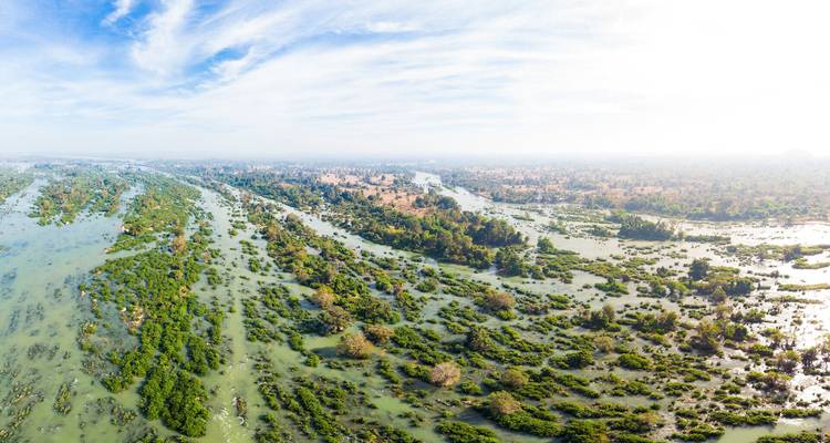 Breite Luftaufnahme eines riesigen Flussdelta mit zahlreichen grünen Inselchen unter einem strahlend blauen Himmel.