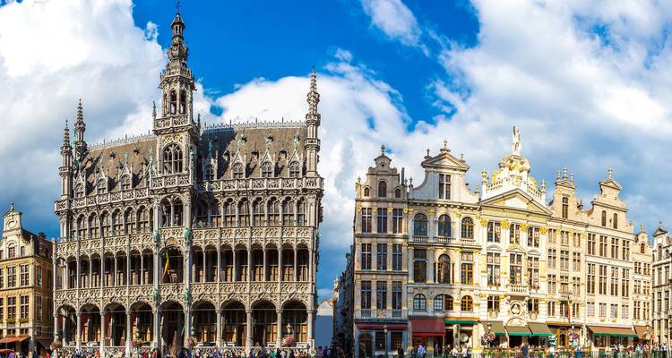 Impressive Gothic and baroque guildhalls of Brussels’ Grand Place packed with visitors under patchy clouds.