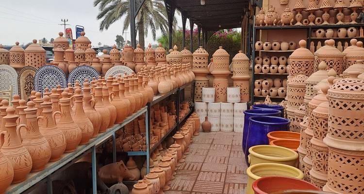 Rows of hand-crafted terracotta pottery and tagines displayed in an open market stall.